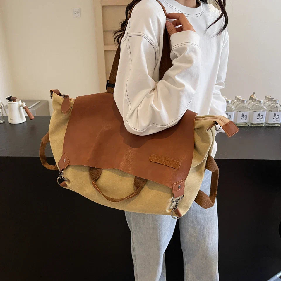 Donna con borsa a tracolla in tela e pelle marrone, stile casual. Accessorio moda versatile per uso quotidiano. Design moderno e funzionale.