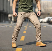 Uomo in strada indossa pantaloni cargo beige, maglietta verde e stivali gialli. Moda urbana, abbigliamento casual maschile, stile outdoor.