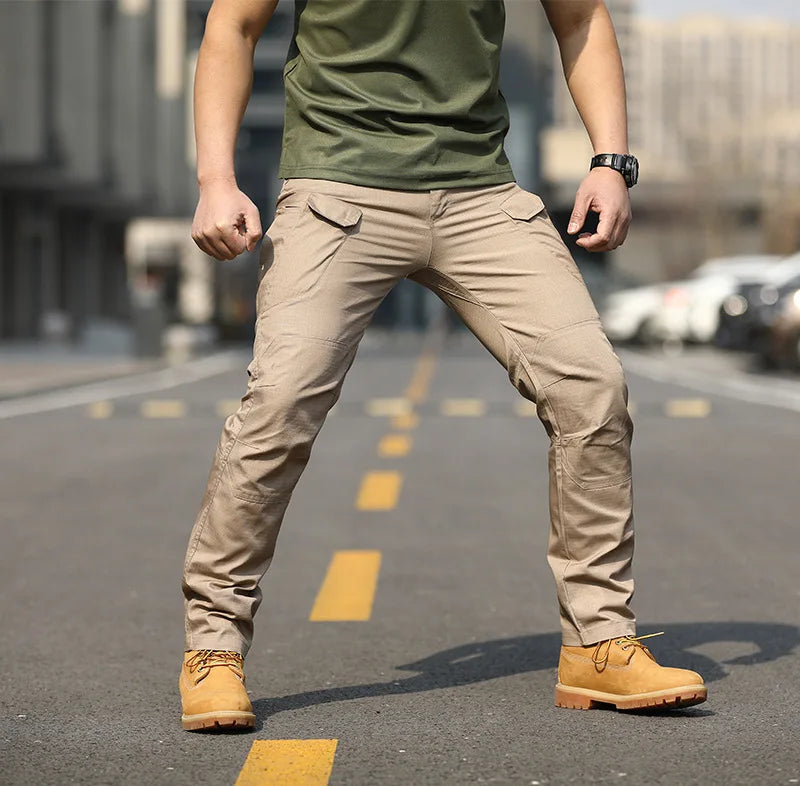 Uomo in strada indossa pantaloni cargo beige, maglietta verde e stivali gialli. Moda urbana, abbigliamento casual maschile, stile outdoor.