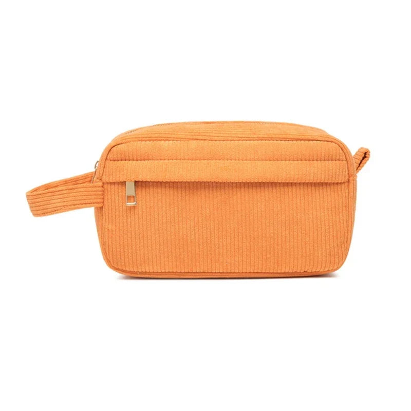 Borsa da toilette arancione in velluto a coste con cerniera, tasca frontale e manico laterale. Elegante e pratica per viaggi e organizzazione.
