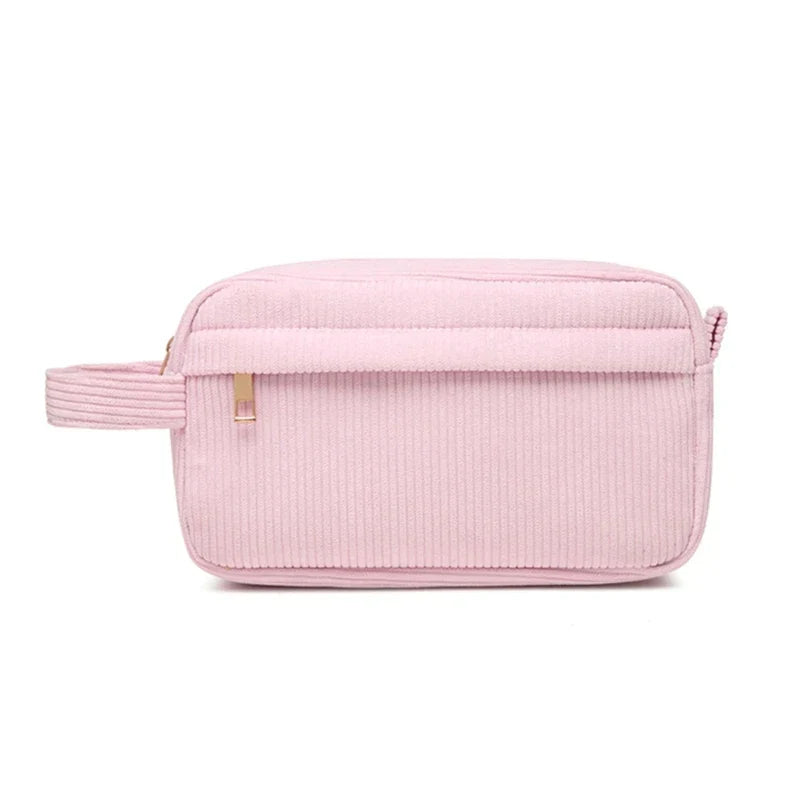 Astuccio da viaggio rosa in velluto a coste con cerniera, design rettangolare, manico laterale, ideale per cosmetici e accessori.
