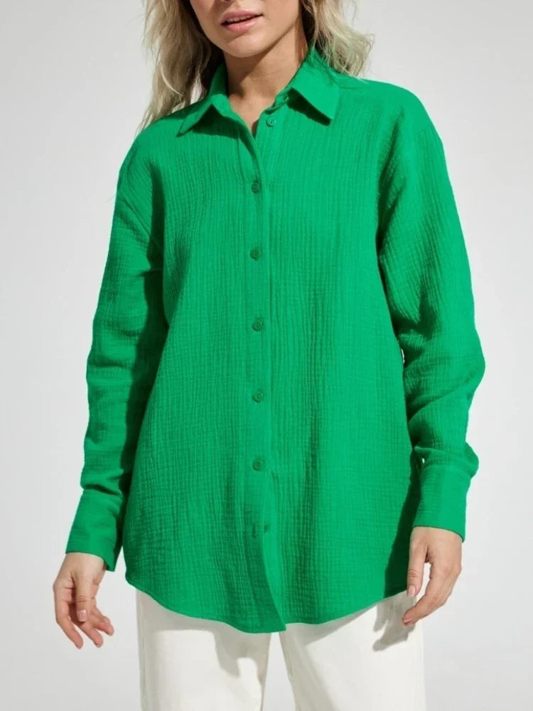 Camicia verde a maniche lunghe in tessuto leggero, con colletto classico e bottoni frontali, indossata da una donna. Moda casual elegante.