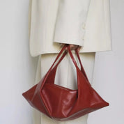 Borsa a mano in pelle rossa, design moderno, indossata con abito bianco elegante. Accessorio moda donna, stile contemporaneo e chic.
