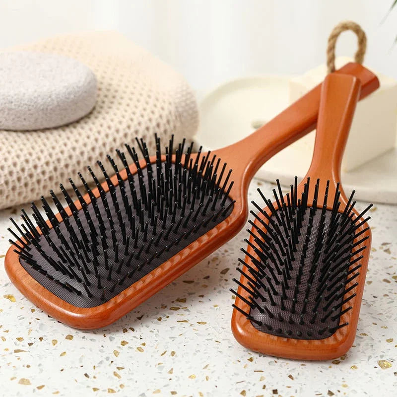 Due spazzole per capelli in legno con setole nere su sfondo chiaro. Accessori per la cura dei capelli, ideali per districare e lisciare.
