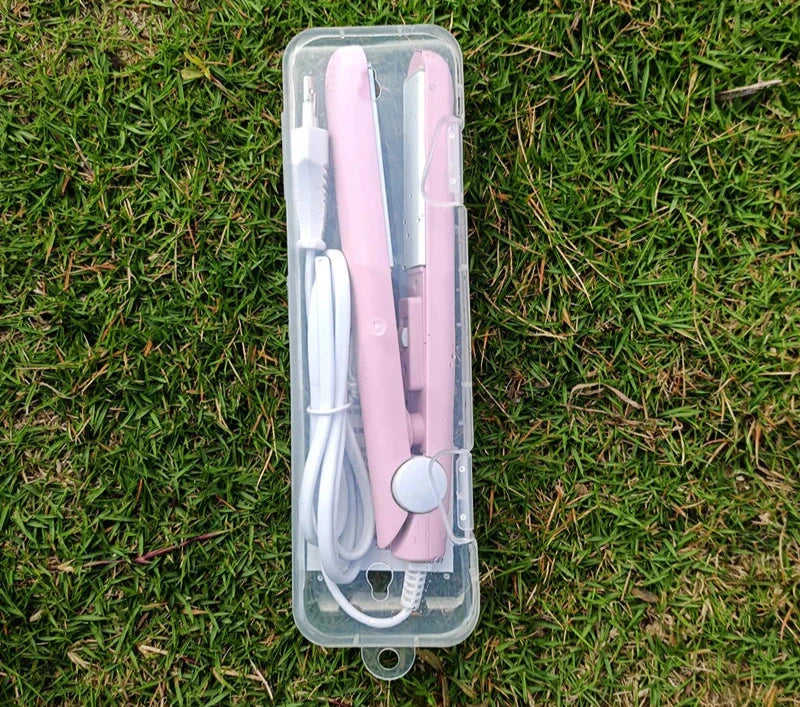 Piastra per capelli rosa portatile in custodia trasparente su erba verde, con cavo USB. Ideale per styling capelli in viaggio.