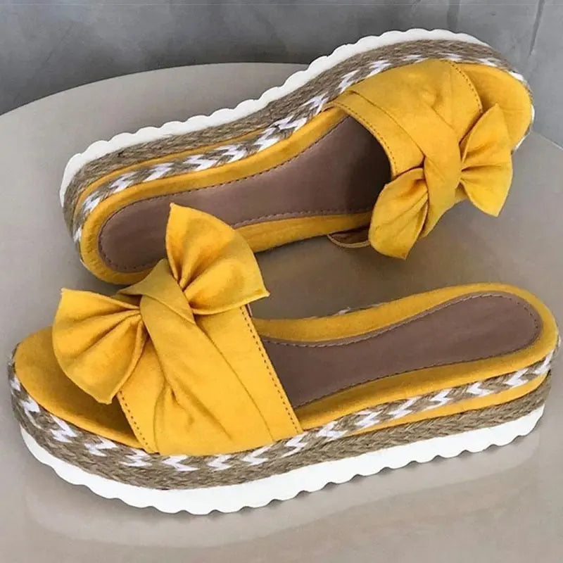 Sandali gialli con zeppa in corda intrecciata, fiocco decorativo, suola bianca ondulata. Scarpe estive eleganti e comode per donna.