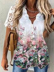 Blusa donna floreale estiva, maniche corte in pizzo bianco, bottoni frontali, colori vivaci, abbinata a jeans e borsa marrone.