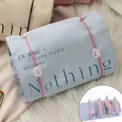 Borsa organizer da viaggio in tessuto grigio con scritta "Nothing", chiusura a cordoncino rosa, tasche interne trasparenti. Accessorio pratico e versatile.
