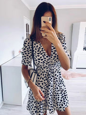 Abito estivo donna bianco e nero a pois, scollo a V, maniche corte, borsa a tracolla, selfie allo specchio, moda casual elegante.