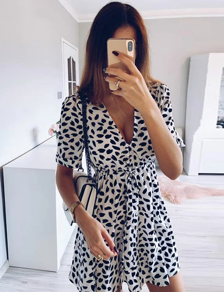 Abito estivo donna bianco e nero a pois, scollo a V, maniche corte, borsa a tracolla, selfie allo specchio, moda casual elegante.