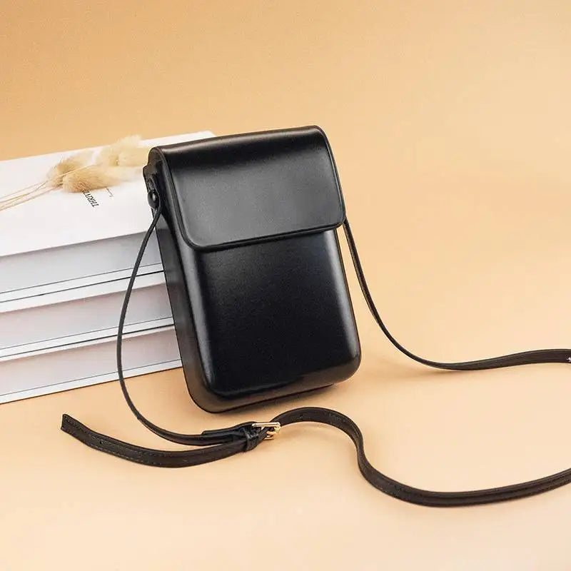 Borsa a tracolla nera in pelle su sfondo beige, design elegante e minimalista, ideale per moda uomo e donna, accessorio versatile e moderno.