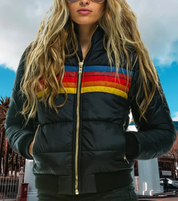 Giacca invernale donna nera con strisce colorate, zip dorata, indossata da modella all'aperto. Moda autunno inverno, abbigliamento casual.