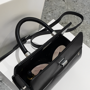 Borsa a tracolla nera in pelle con chiusura metallica, manici robusti e interno spazioso. Elegante accessorio moda per donna.