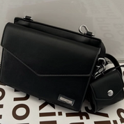 Borsa a tracolla nera elegante in pelle con chiusura a patta, dettagli metallici argentati e mini pochette abbinata. Accessorio moda donna.