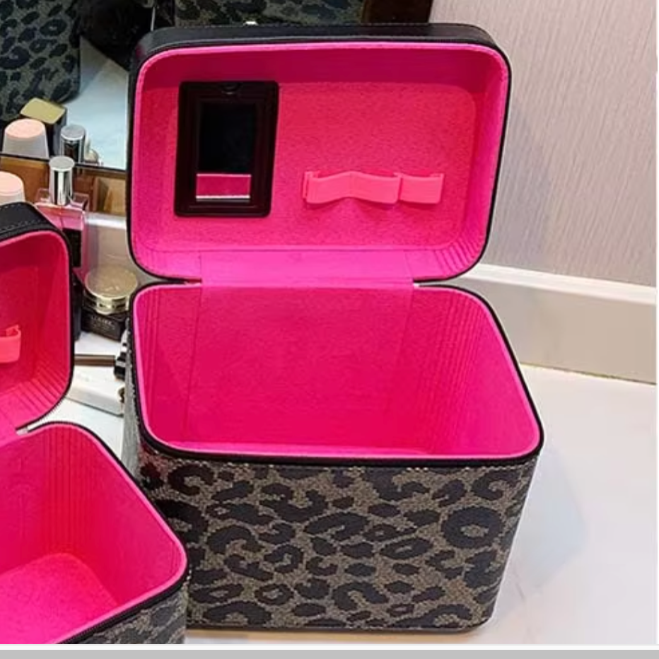 Beauty case leopardato aperto con interno rosa, specchio e scomparti per cosmetici. Ideale per organizzare trucchi e accessori da viaggio.