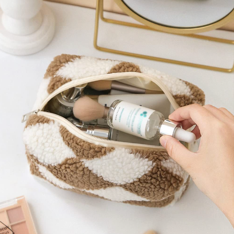 Borsa trucco in tessuto a scacchi beige e bianco, contenente pennelli e flacone di siero. Accessori cosmetici, beauty case elegante.