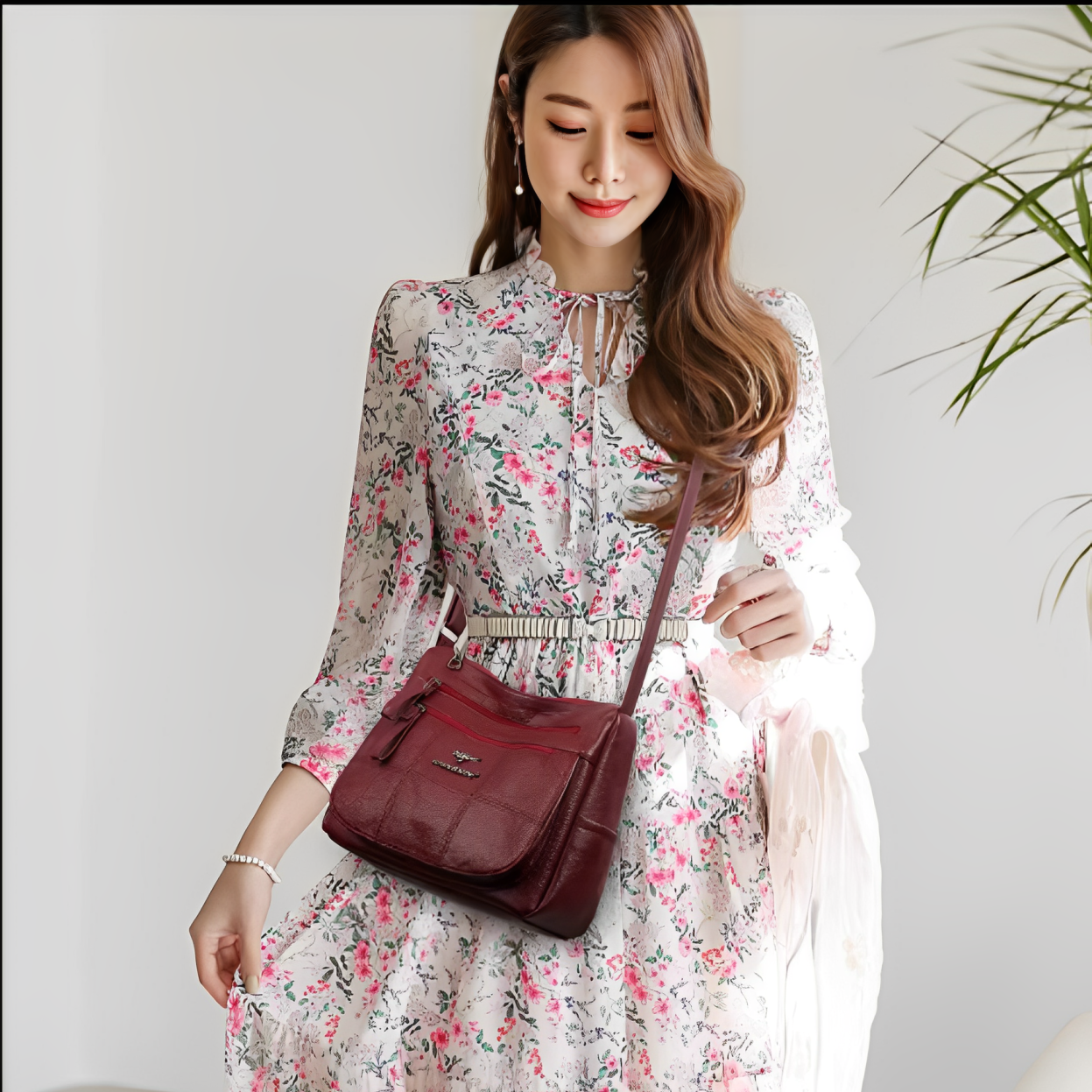 Donna con abito floreale e borsa a tracolla in pelle bordeaux, moda femminile elegante, accessori di tendenza, stile primaverile.
