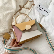Borsa a tracolla multicolore in pelle con catena dorata, design geometrico, manico superiore e tracolla regolabile su sfondo bianco.