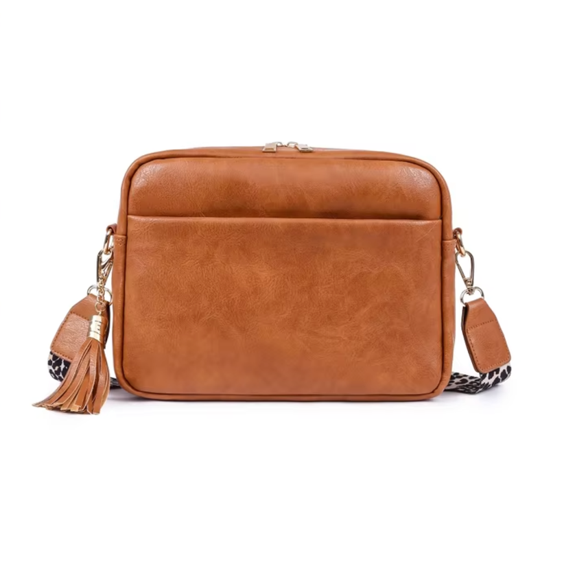 Borsa a tracolla in pelle marrone con nappina decorativa, tasca frontale e tracolla regolabile. Elegante accessorio moda donna.
