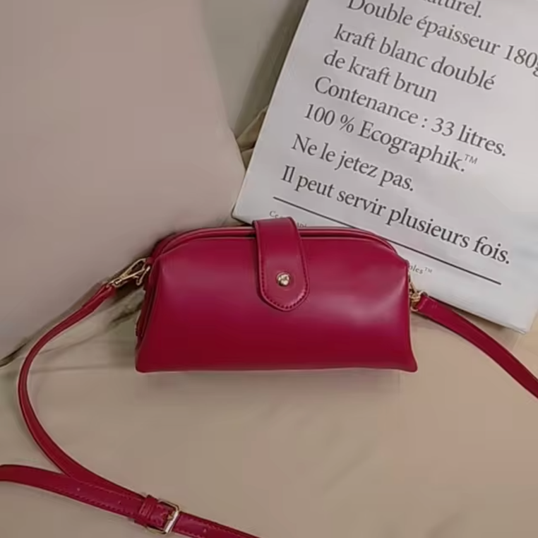 Borsa a tracolla in pelle rossa su sfondo beige, design elegante con chiusura a bottone dorato. Accessorio moda donna, stile casual chic.