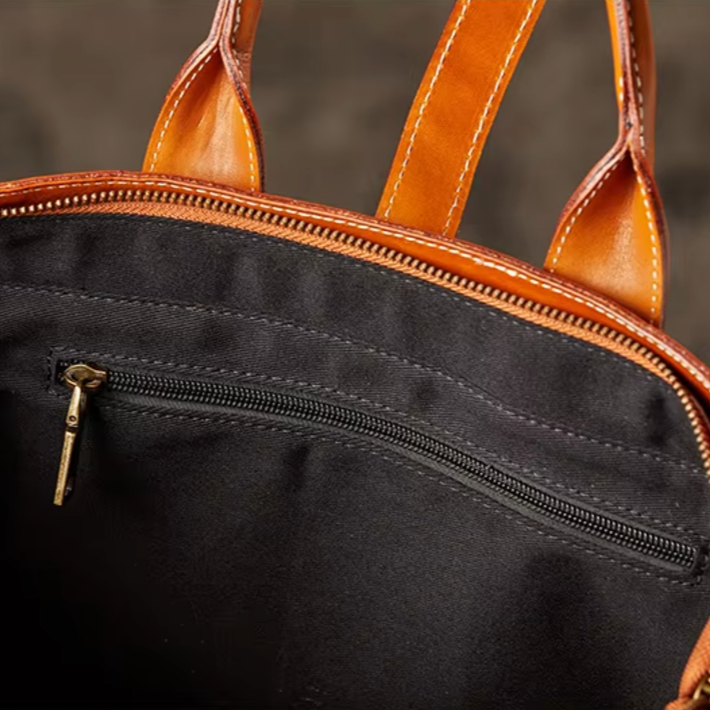 Borsa in pelle marrone con cerniera, manici robusti e tasca interna nera. Design elegante e funzionale per moda e praticità quotidiana.