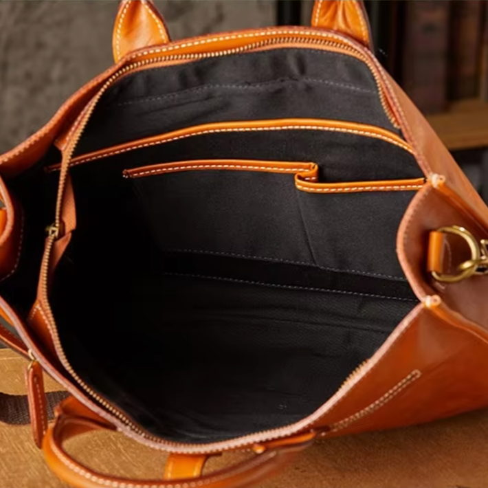 Borsa in pelle marrone aperta, con tasche interne nere e cuciture a contrasto. Design elegante, ideale per moda donna e accessori di lusso.