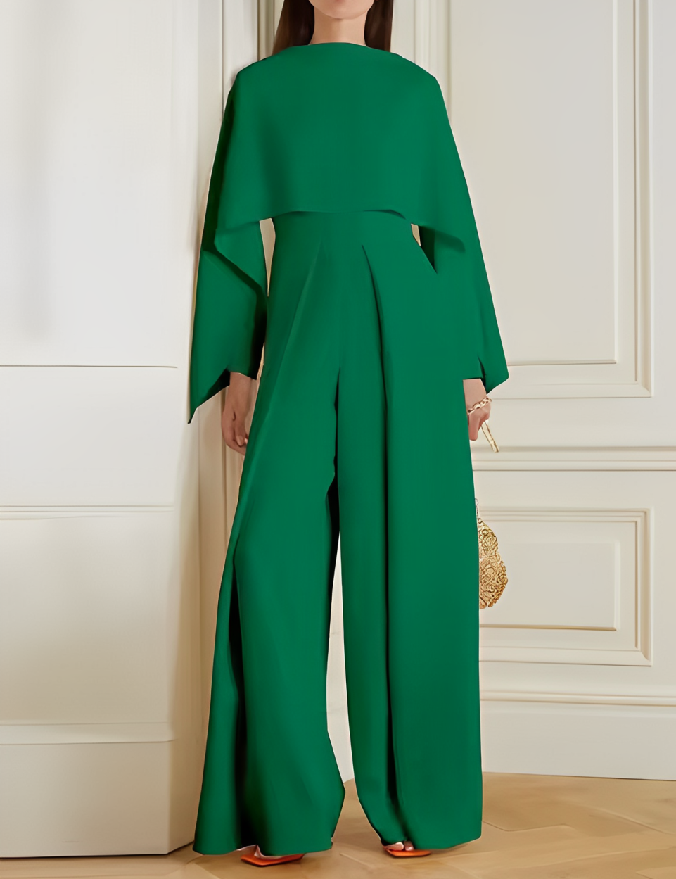 Tuta elegante verde smeraldo con maniche ampie e pantaloni larghi, indossata da una donna in un ambiente interno. Moda femminile, abbigliamento chic.