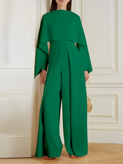 Tuta elegante verde smeraldo con maniche ampie e pantaloni larghi, indossata da una donna in un ambiente interno. Moda femminile, abbigliamento chic.