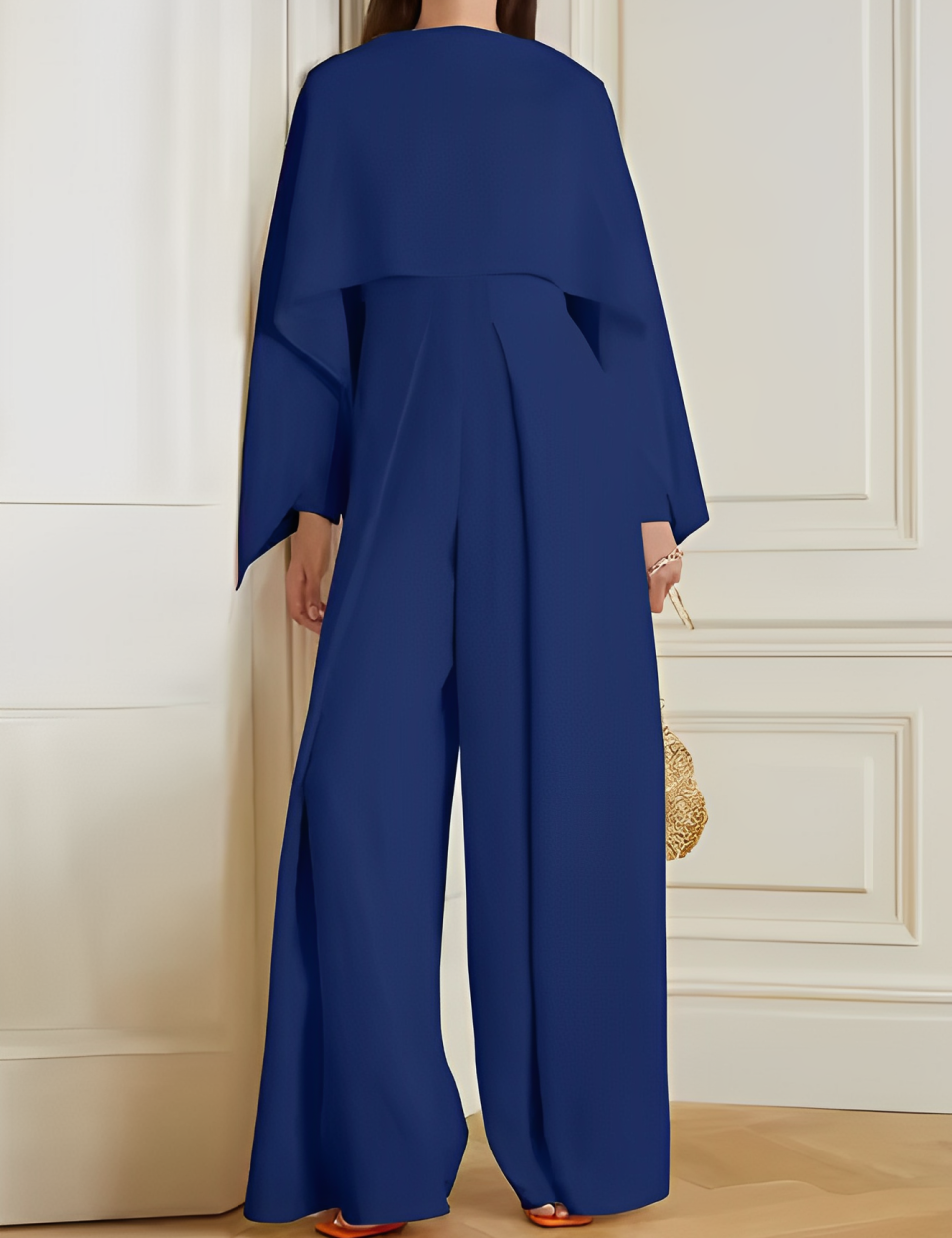 Tuta elegante blu donna, maniche ampie, pantaloni larghi, moda contemporanea, abbigliamento femminile, stile sofisticato, sfondo interno.