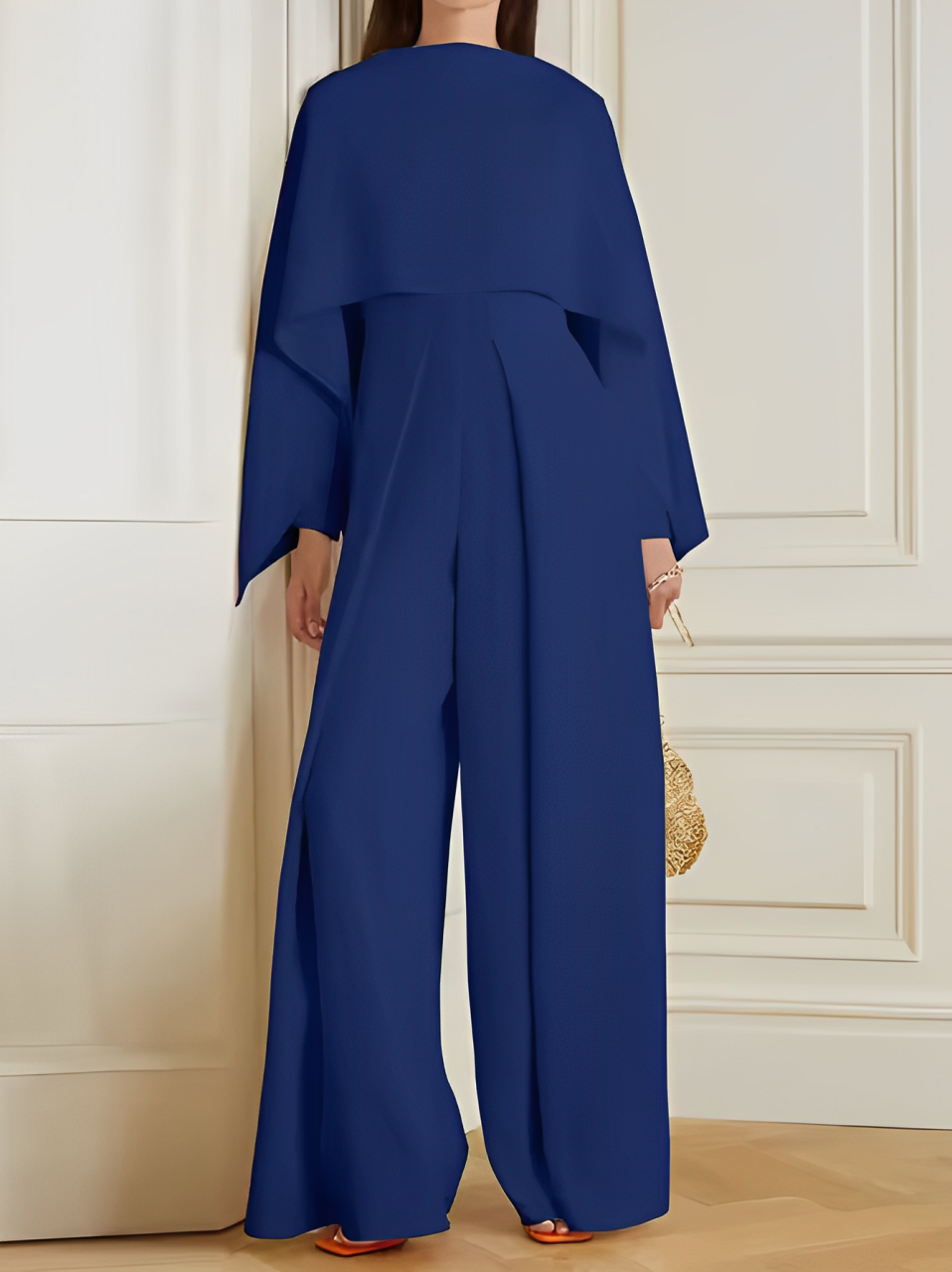 Tuta elegante blu donna, maniche ampie, pantaloni larghi, moda contemporanea, abbigliamento femminile, stile sofisticato, sfondo interno.