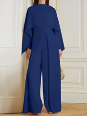 Tuta elegante blu donna, maniche ampie, pantaloni larghi, moda contemporanea, abbigliamento femminile, stile sofisticato, sfondo interno.