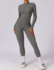 Tuta intera grigia da donna, a maniche lunghe, con zip frontale. Design aderente, ideale per fitness e yoga. Scarpe sportive bianche incluse.