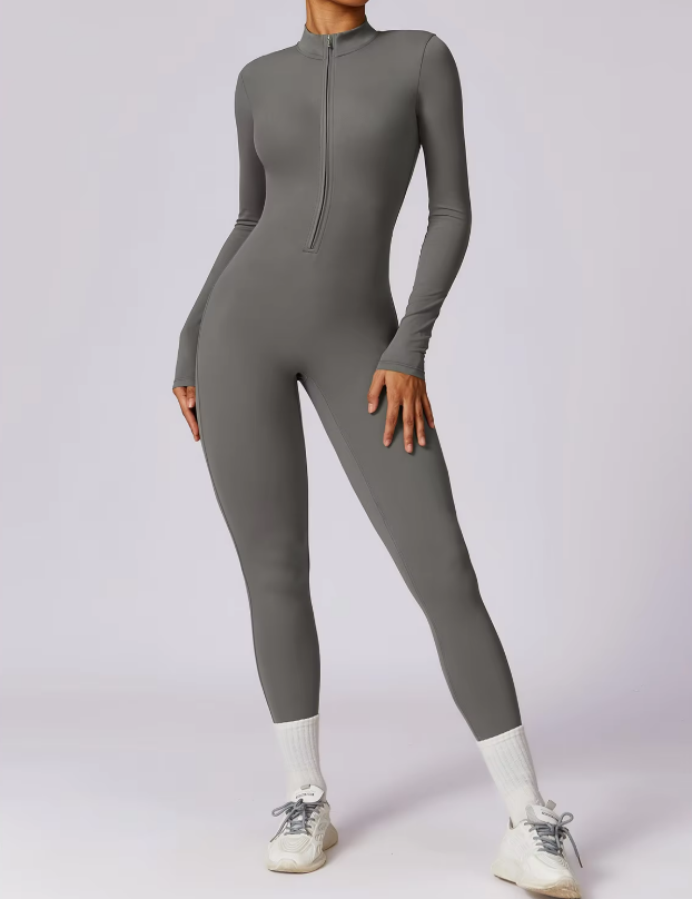 Tuta intera grigia da donna, a maniche lunghe, con zip frontale. Design aderente, ideale per fitness e yoga. Scarpe sportive bianche incluse.