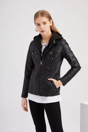 Giacca in pelle nera da donna con cappuccio, chiusura a zip, tasche multiple, indossata su maglia bianca e pantaloni neri. Moda casual elegante.