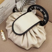Borsa a mano beige con manico nero decorato, design elegante e moderno, perfetta per moda femminile. Accessorio chic per ogni occasione.
