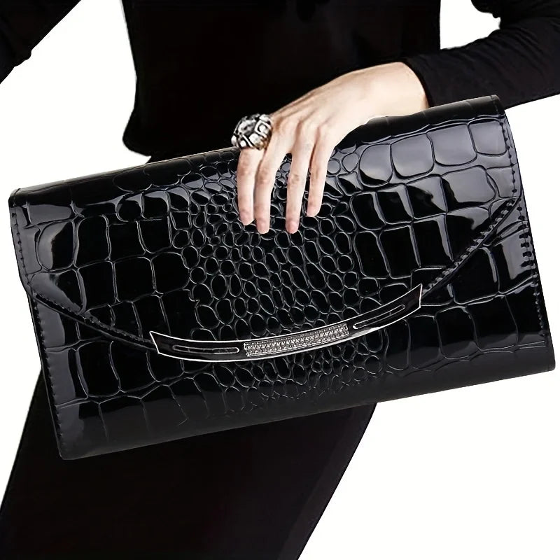 Borsa clutch nera in pelle effetto coccodrillo, elegante e lucida, con chiusura metallica. Accessorio moda donna, perfetto per eventi serali.