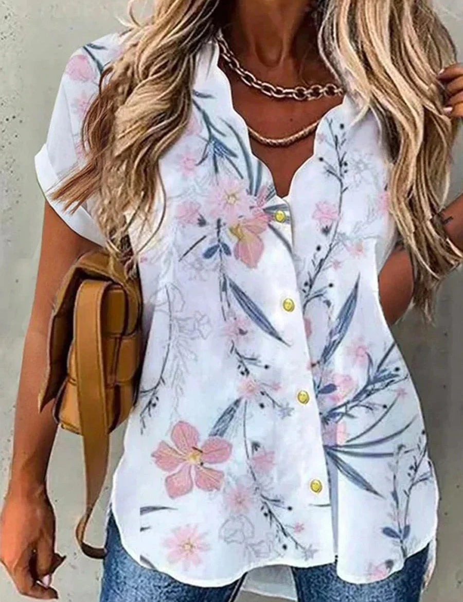 Camicia estiva da donna con stampa floreale, maniche corte, bottoni gialli, scollo a V, abbinata a jeans e borsa marrone. Moda casual elegante.