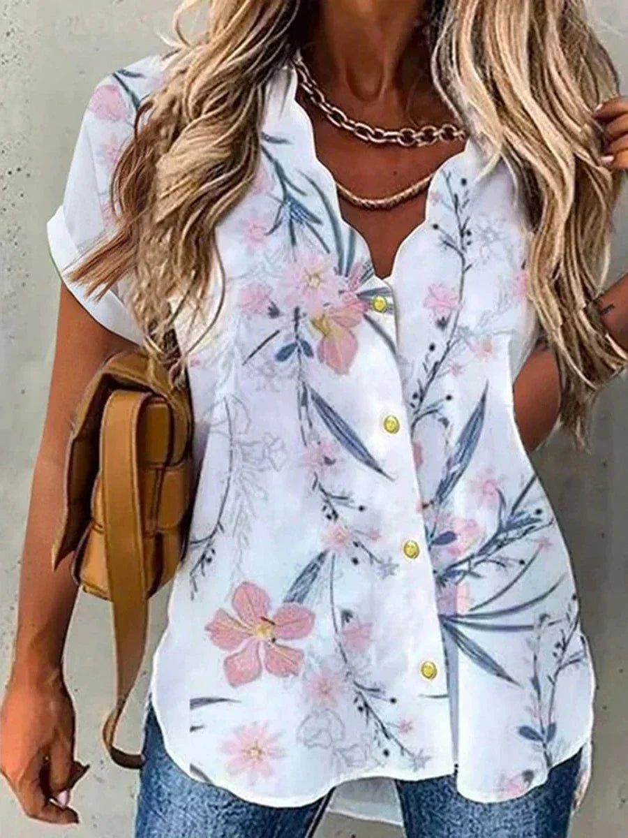Camicia estiva da donna con stampa floreale, maniche corte, bottoni gialli, scollo a V, abbinata a jeans e borsa marrone. Moda casual elegante.