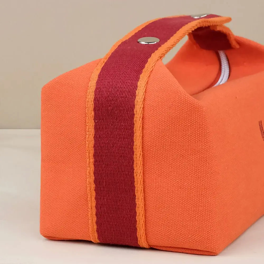 Borsa da toilette arancione con manico rosso, chiusura a zip, design moderno. Accessorio da viaggio, pratico e resistente.