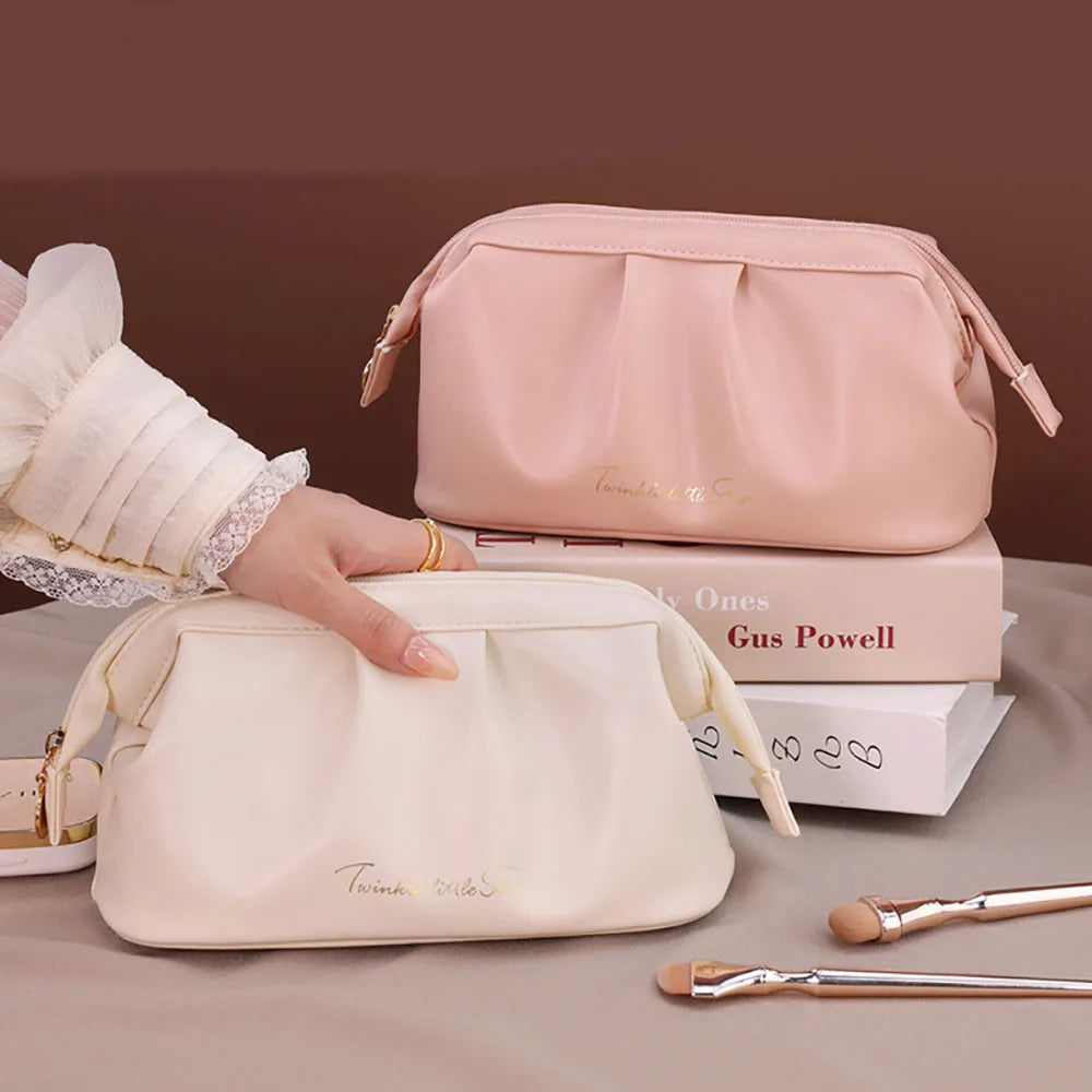 Due eleganti borse cosmetiche in pelle rosa e bianca su libri, con pennelli trucco. Design moderno, ideale per organizzare accessori di bellezza.