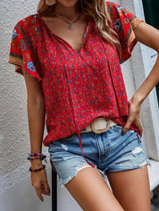 Donna con blusa rossa floreale e pantaloncini di jeans strappati. Moda estiva casual, abbigliamento femminile trendy, stile boho chic.