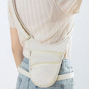 Zaino monospalla beige in tessuto, con doppia cerniera, indossato su maglia a coste e jeans. Accessorio moda casual e pratico per donna.