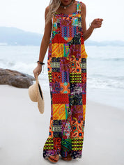 Donna in abito lungo patchwork colorato su spiaggia, con cappello di paglia in mano. Moda estiva, abbigliamento boho chic, look casual mare.