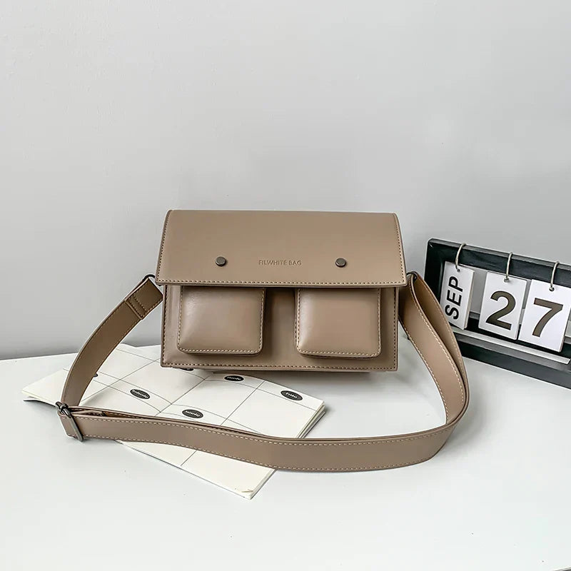 Borsa a tracolla beige con doppia tasca frontale, design minimalista, su sfondo grigio. Accessorio moda elegante per donna.