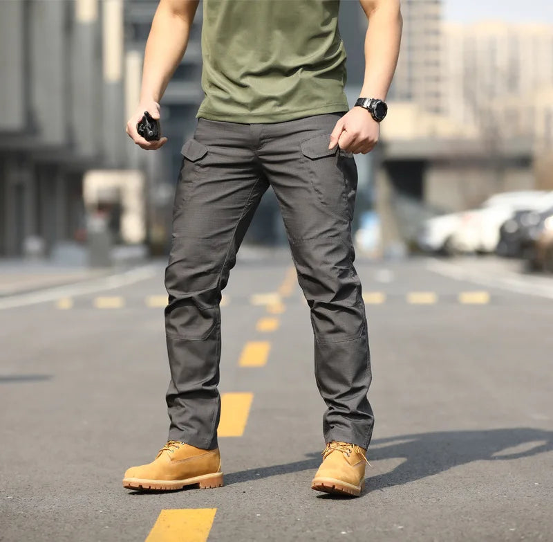 Uomo in pantaloni cargo grigi e stivali gialli su strada urbana. Moda maschile casual, abbigliamento outdoor, pantaloni resistenti, stile urbano.