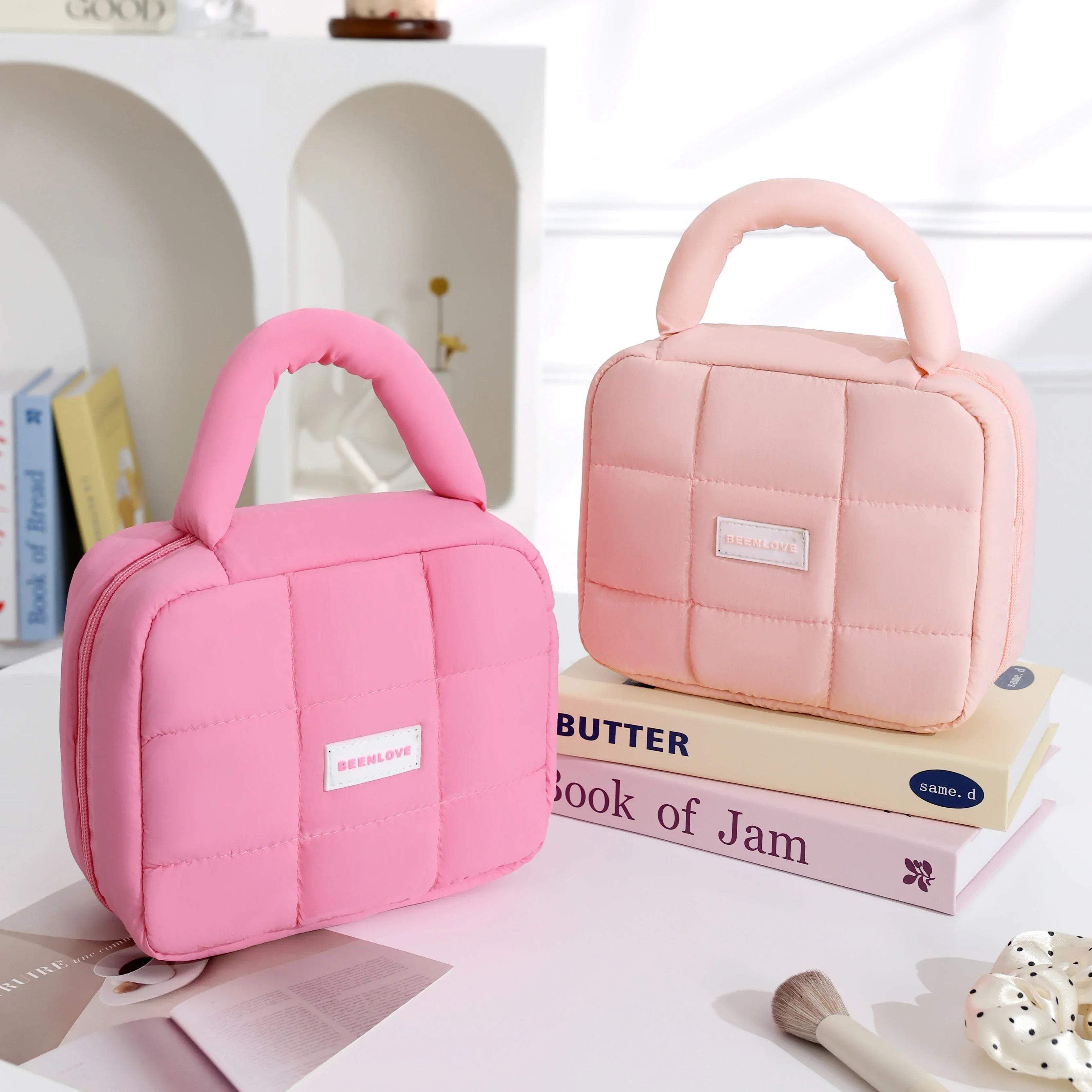 Due borse termiche rosa e rosa chiaro su scaffale bianco, design trapuntato, manico imbottito, ideali per pranzo al sacco. Accessori moda pratici.