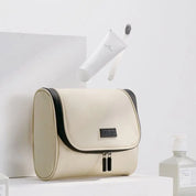 Borsa da toilette beige con cerniera nera, design elegante, ideale per viaggi. Include flacone bianco per cosmetici. Accessori bagno moderni.