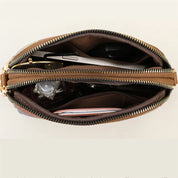 Borsa a tracolla in pelle marrone con doppia cerniera, vista dall'alto. Interno spazioso con scomparti per accessori e documenti. Elegante e funzionale.