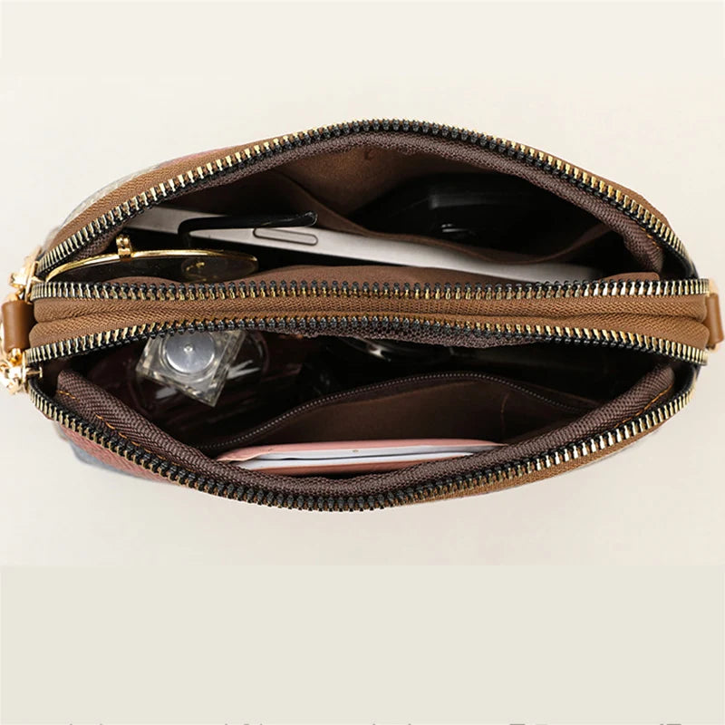 Borsa a tracolla in pelle marrone con doppia cerniera, vista dall'alto. Interno spazioso con scomparti per accessori e documenti. Elegante e funzionale.