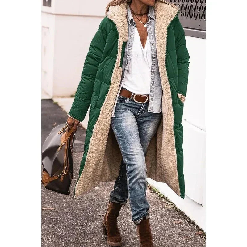 Cappotto lungo verde con fodera in pelliccia sintetica, indossato con jeans e stivali marroni. Moda invernale donna, stile casual chic.